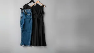 Διπλωμένο τζιν παντελόνι δίπλα σε μαύρο βραδινό φόρεμα σε κρεμάστρα